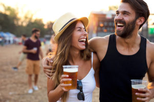 man and woman laughing while each holding a beer